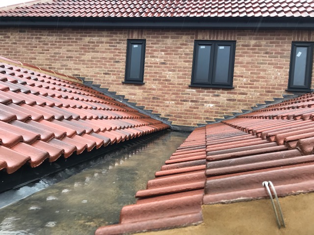Tiled roof meeting a brick wall with a lead flashing detail