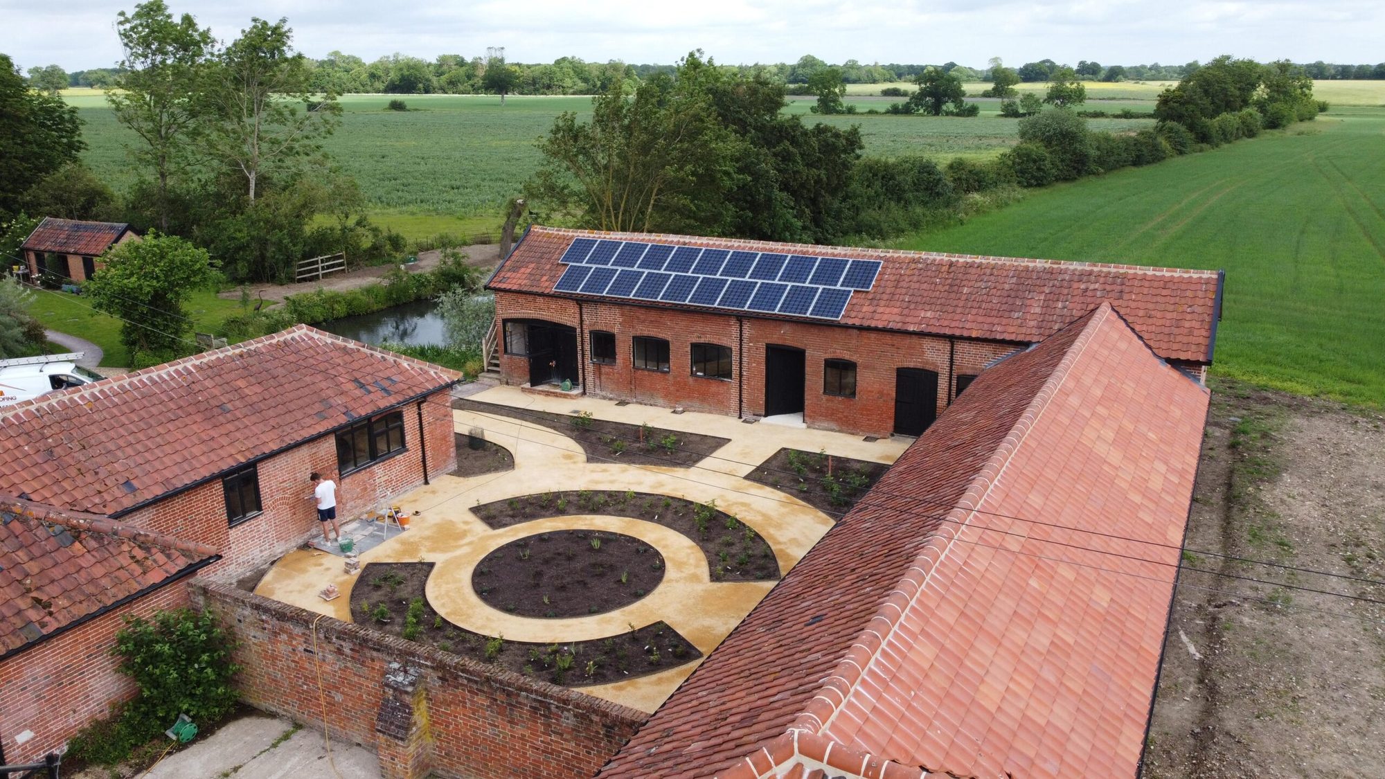 Aerial view of a barn courtyard with red tiled roofs and solar panels