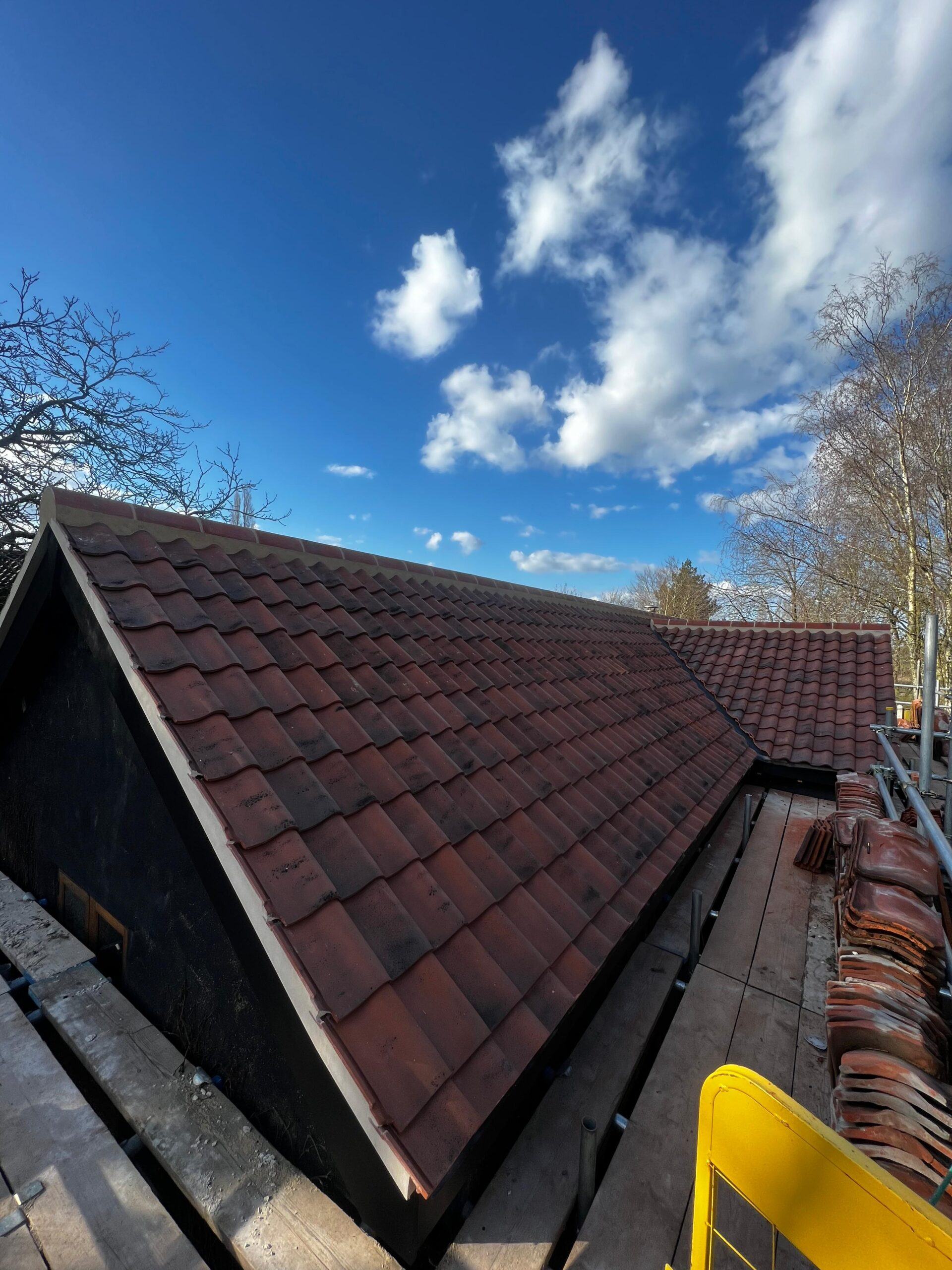 Dark tiled roof slope under a blue sky