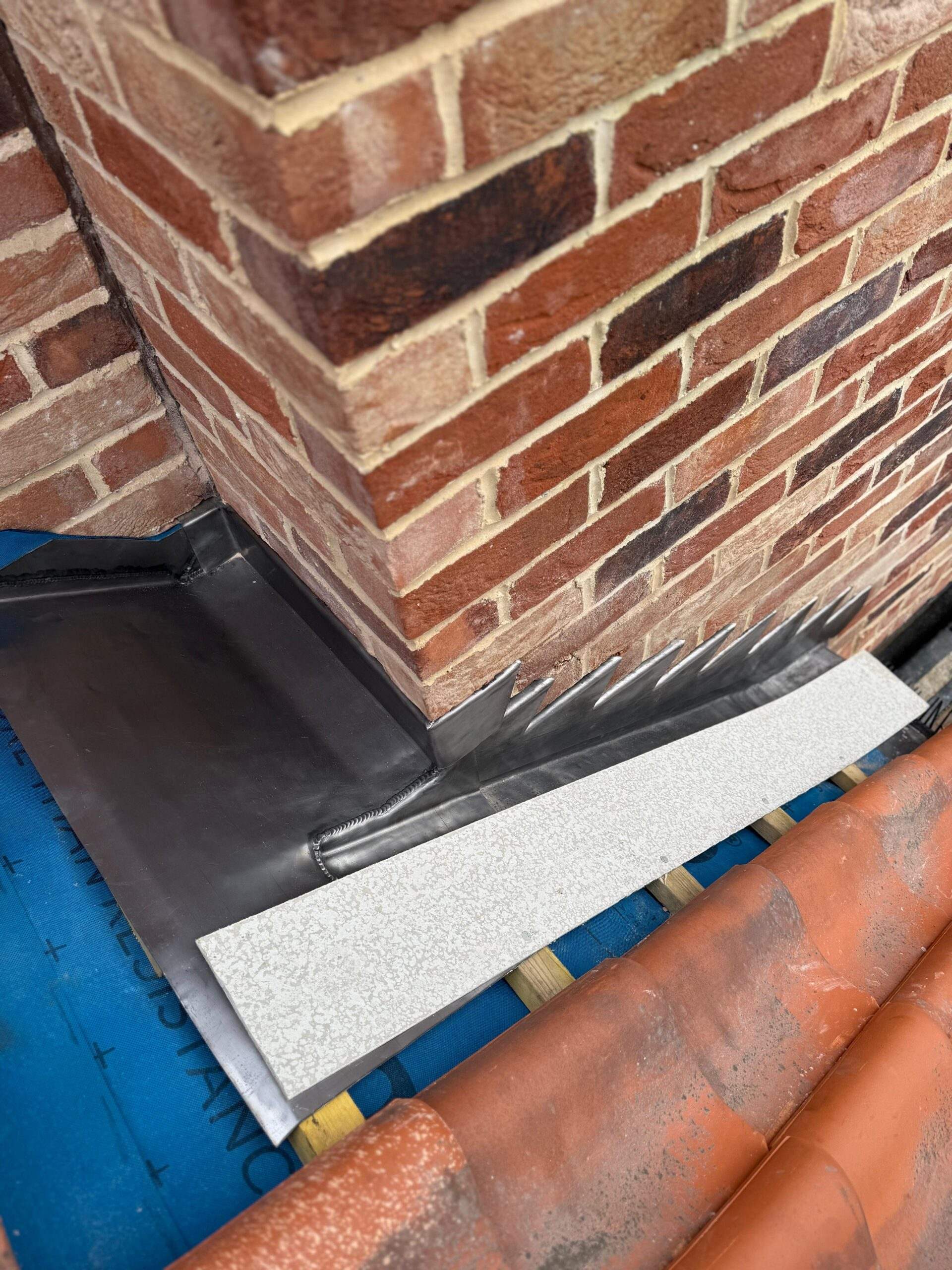 Lead flashing fitted where a brick chimney meets the roof tiles